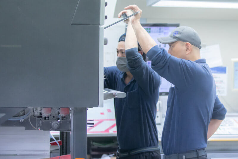 印刷機の様子を見ている印刷オペレーターの画像